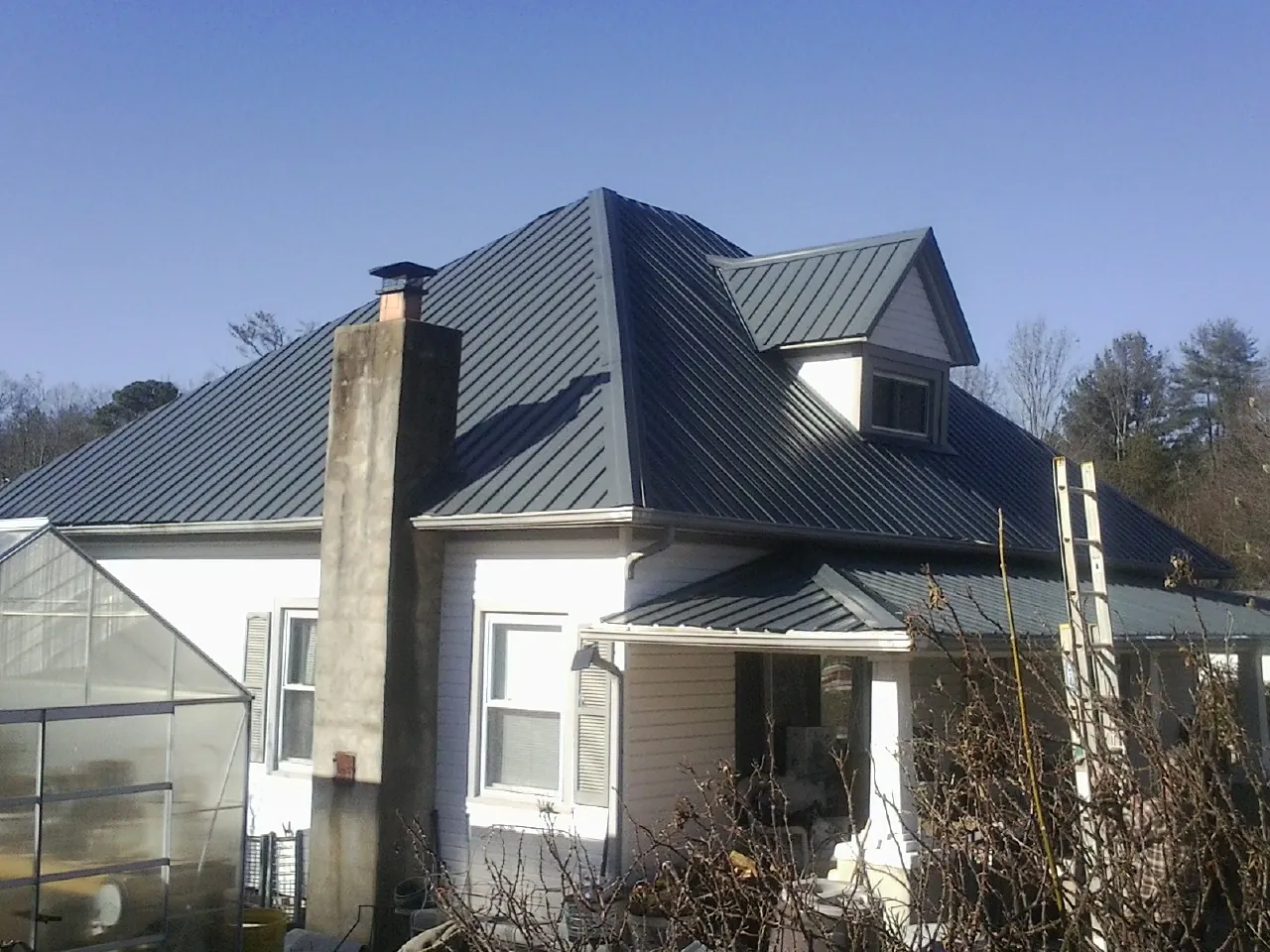 Dark blue standing seam metal roof on a white farmhouse with dormer — Slate & Tile Roof Repair by Roofing Brothers in Tehama