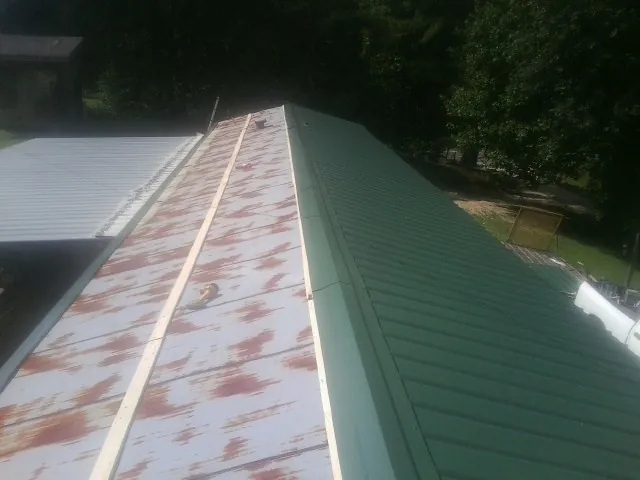 Old rusted panels beside newly installed green metal roofing — Wind Damage Roof Repair by Roofing Brothers in Tehama