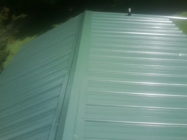 New green metal panels meeting at the ridge of a roof — Flat Roof Repair work by our crew in Tehama