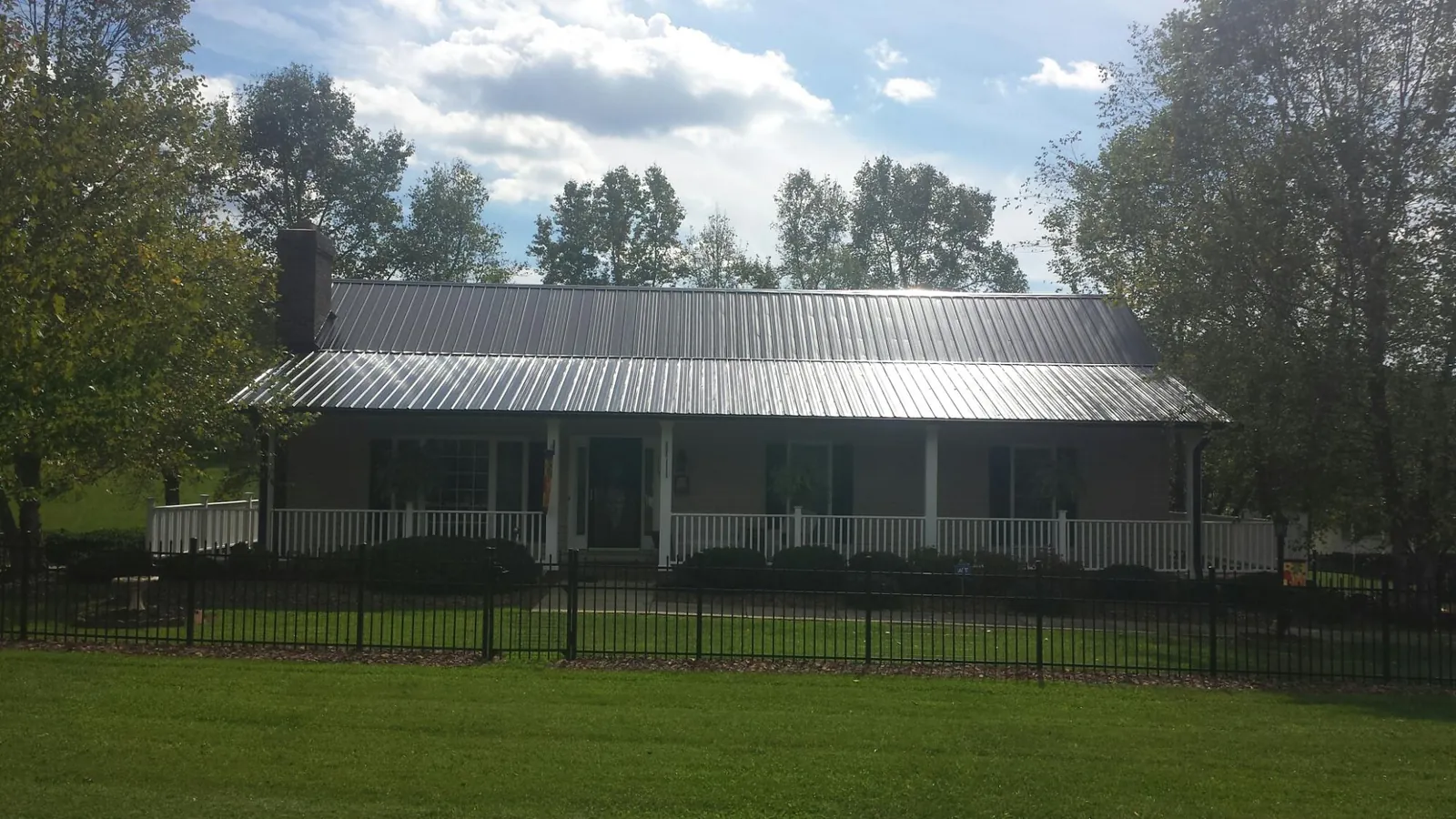 Gray metal roof on a brick ranch with a full width front porch — Gutter Guard Installation work by our crew in Tehama