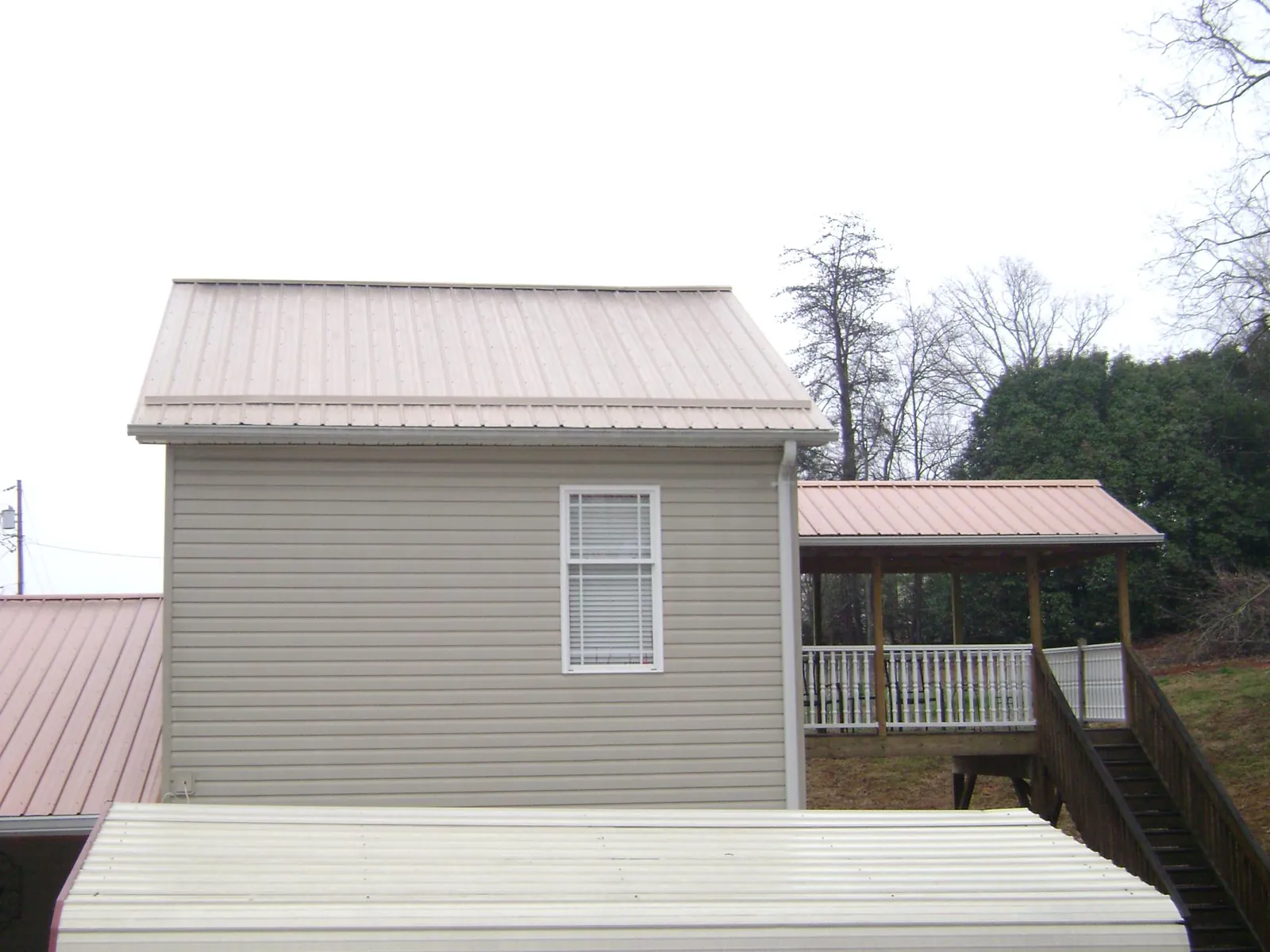 Tan metal roofs on a two story addition and attached porch, from a Roof Replacement job in Tehama