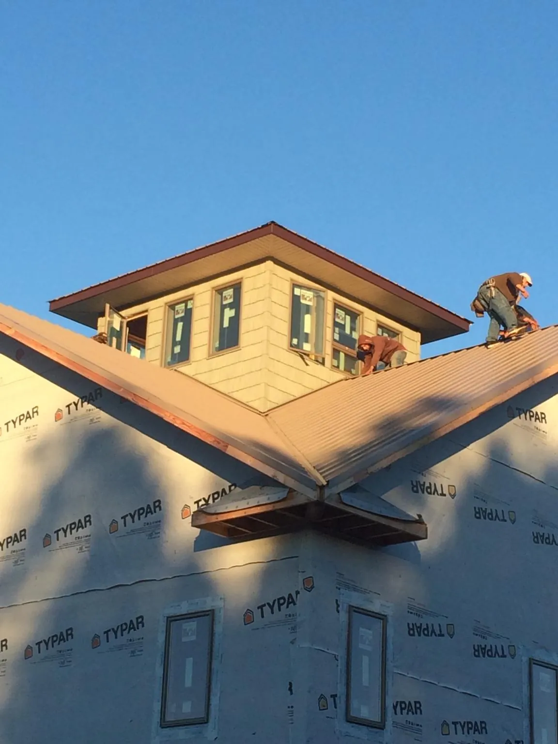 Roofers working around a rooftop cupola on a new metal roof at sunset — Roof Waterproofing in Tehama by Roofing Brothers